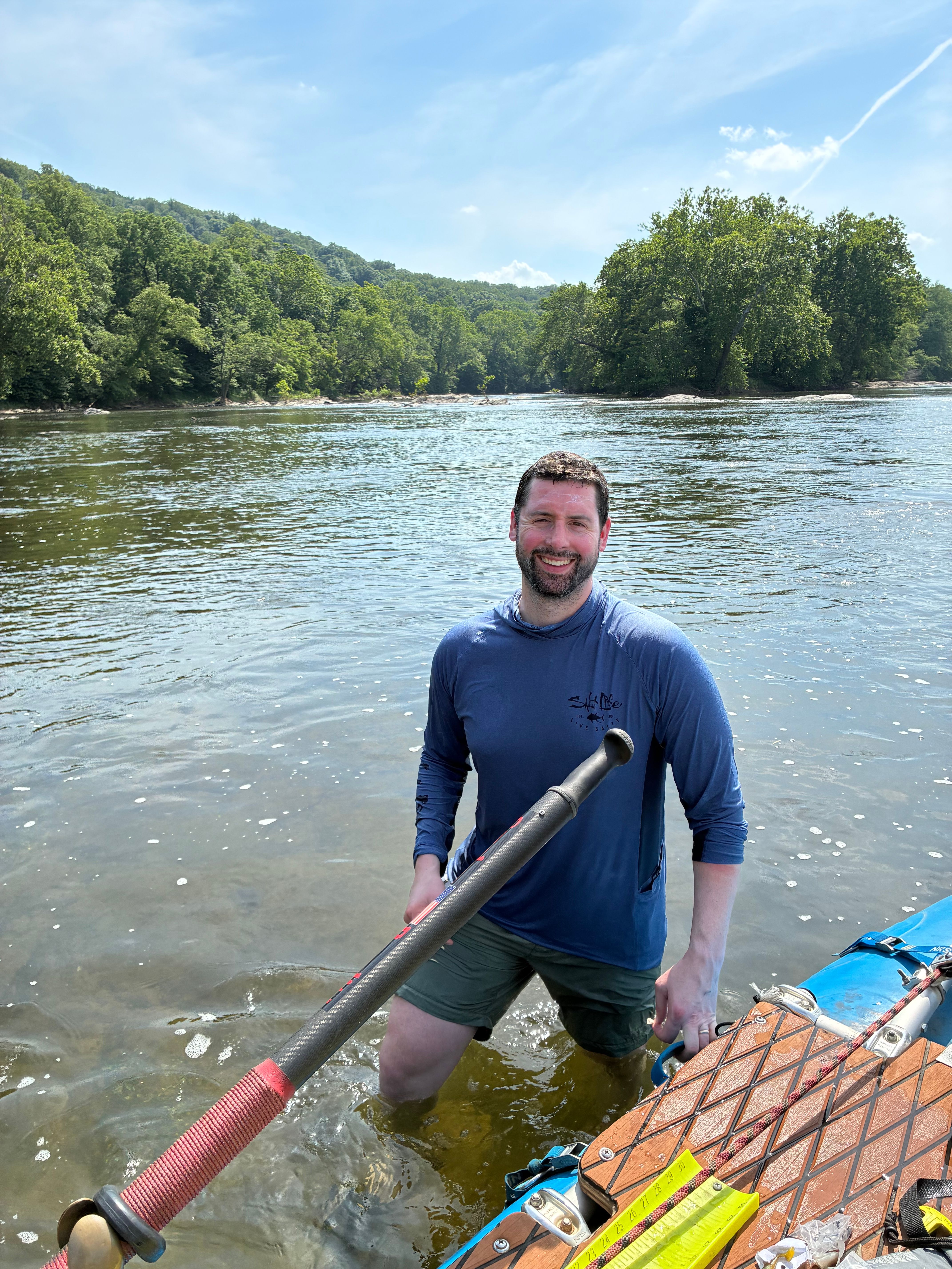 Person holding freshly caught fish while standing in water near wooden dock