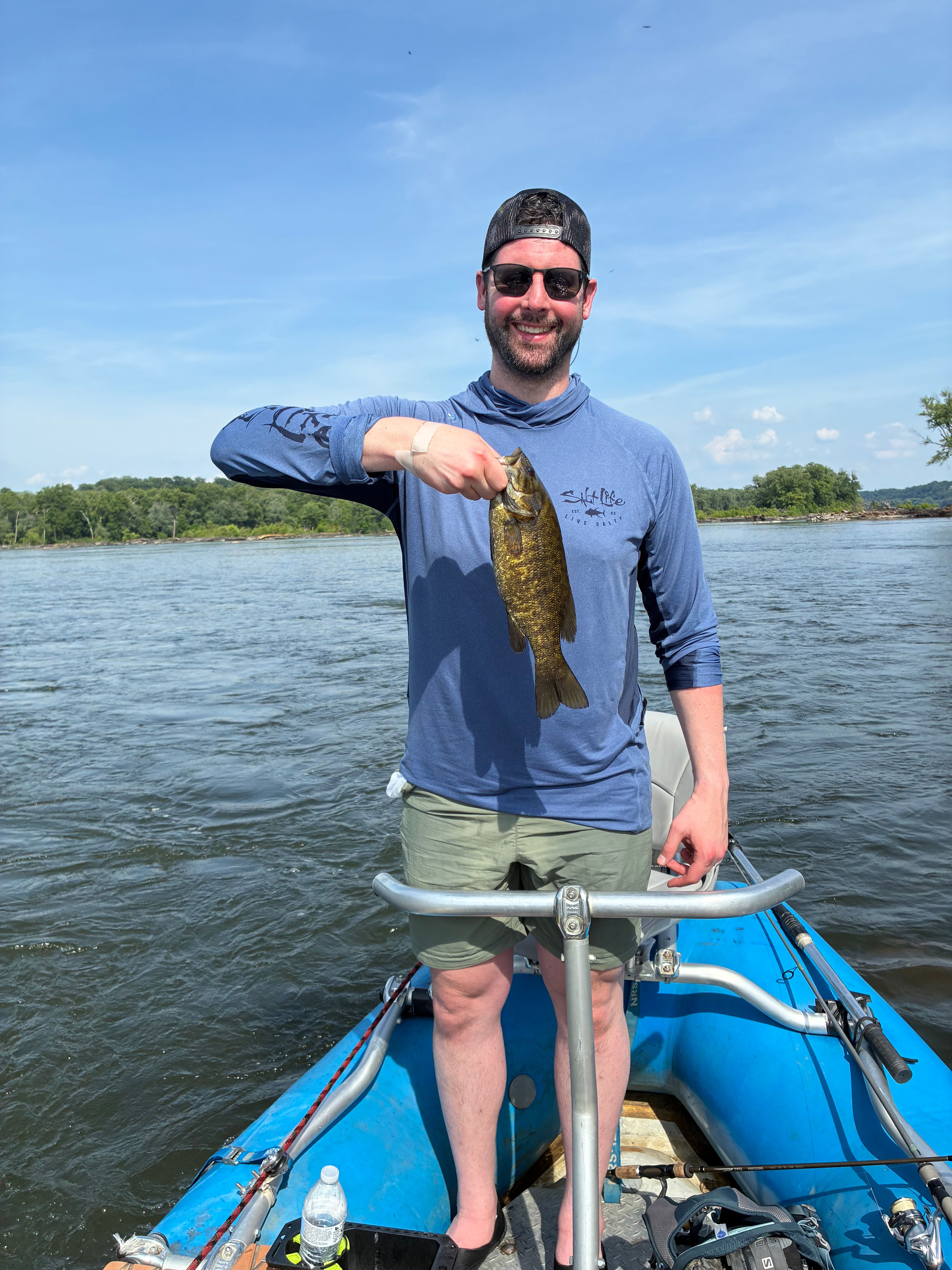 Angler holding freshly caught smallmouth bass on fishing boat