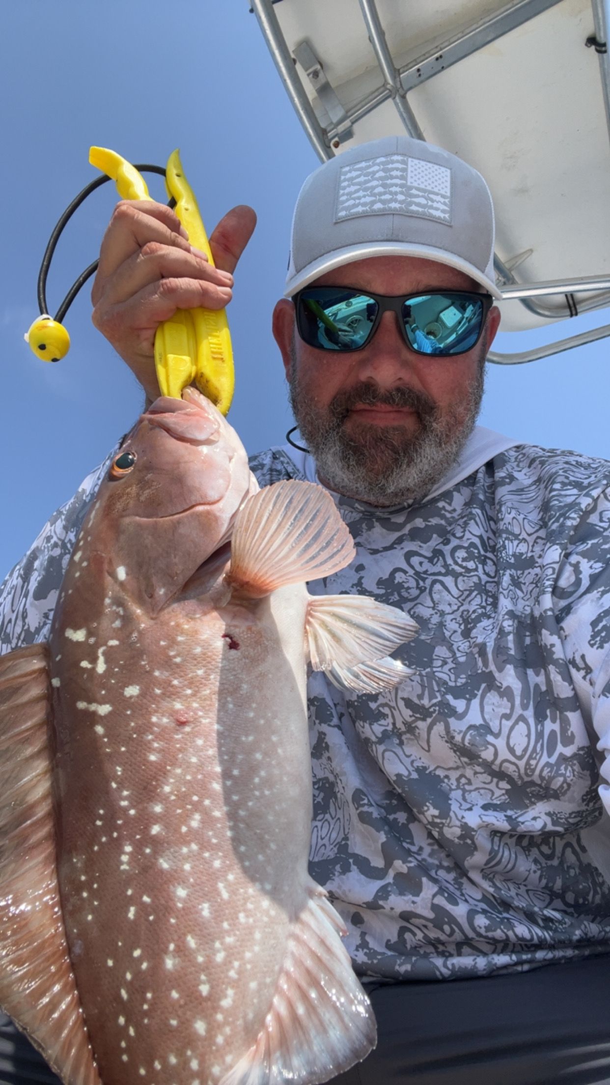 Red grouper caught while fishing on boat with yellow pliers