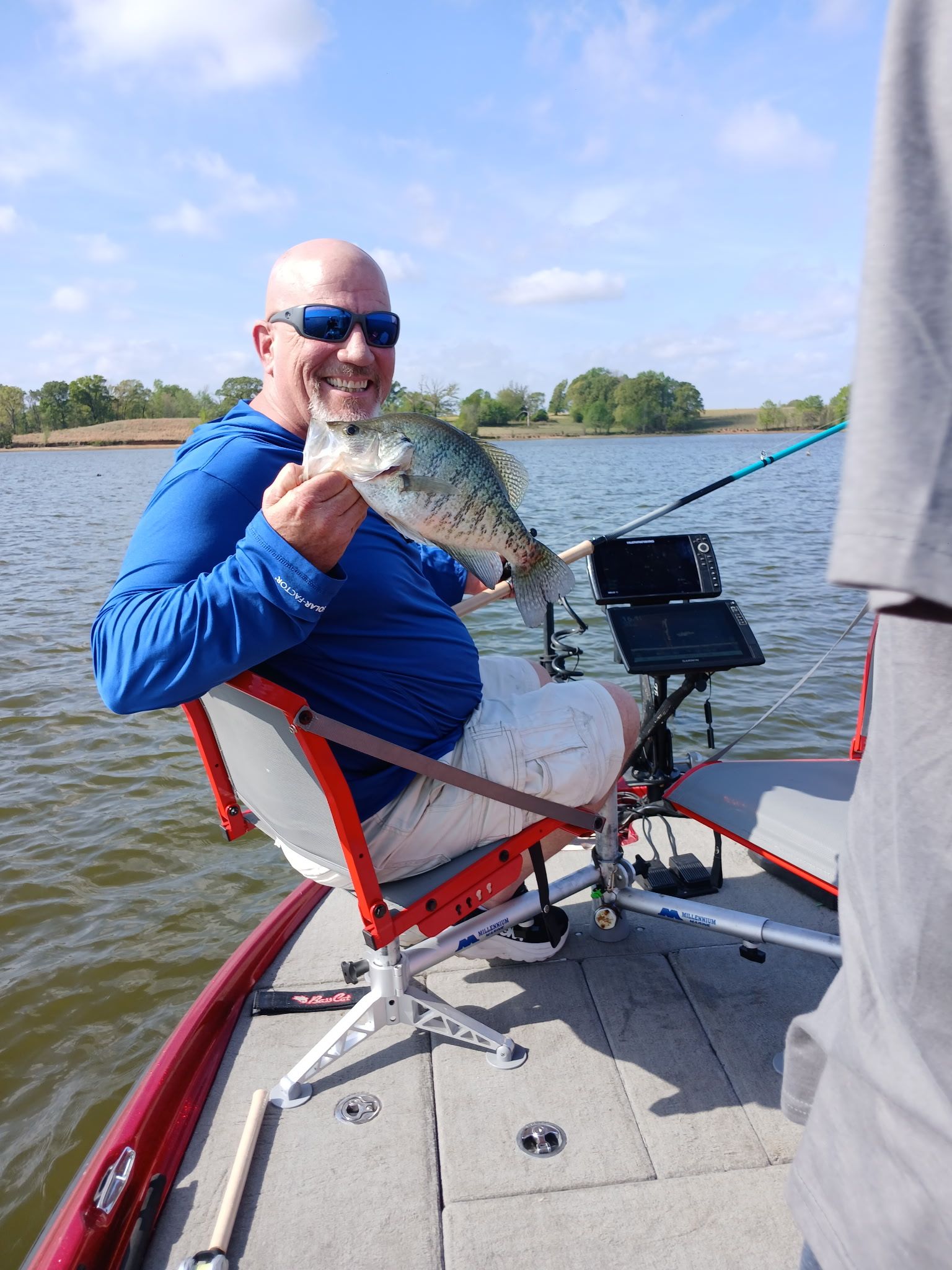 Angler holding caught fish on fishing boat with electronics and equipment visible