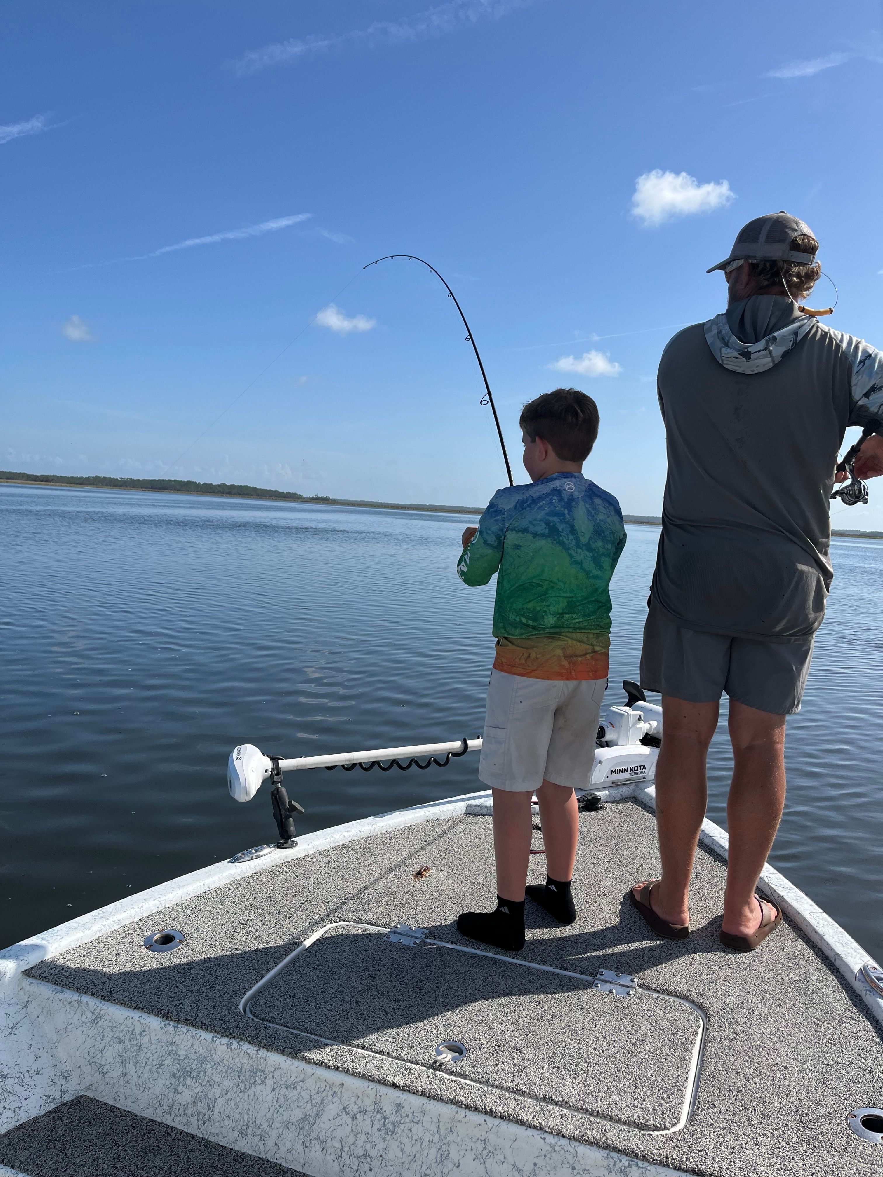 Fishing rod bent while fighting fish on boat deck over ocean water