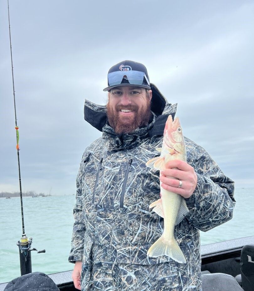 Angler holding freshly caught fish on boat during fishing trip