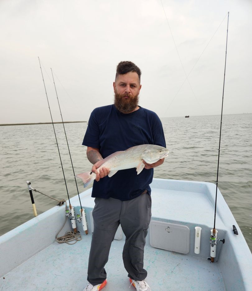 Angler holding freshly caught fish on fishing boat with rods and tackle