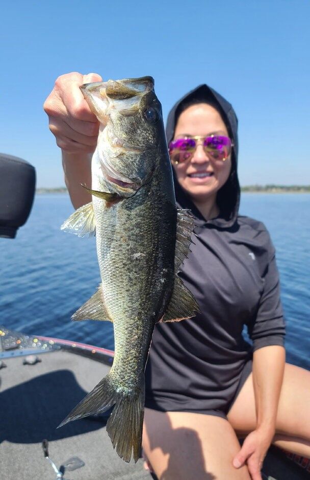 Angler holding freshly caught bass on boat during fishing trip