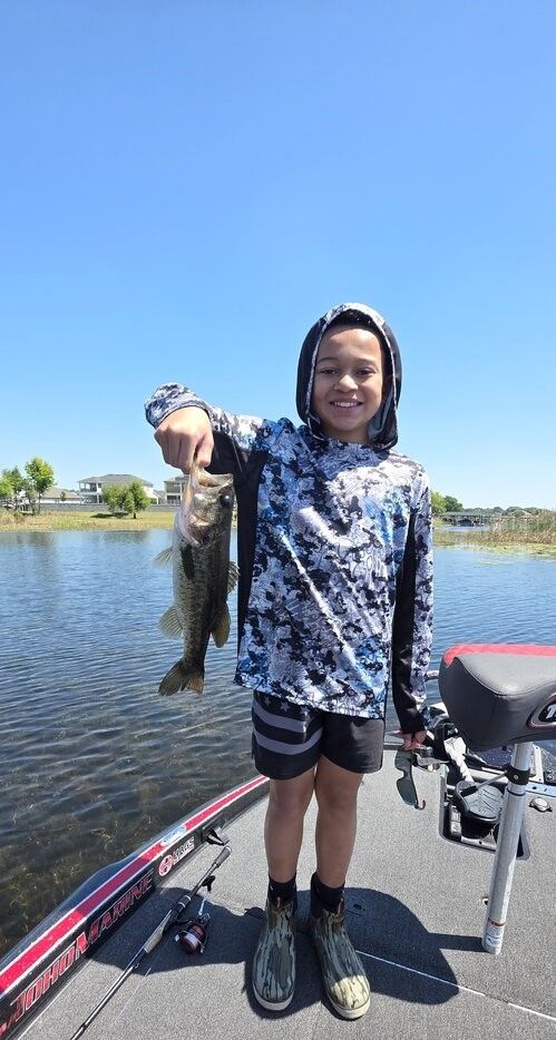 Bass fish being held up on fishing boat on lake