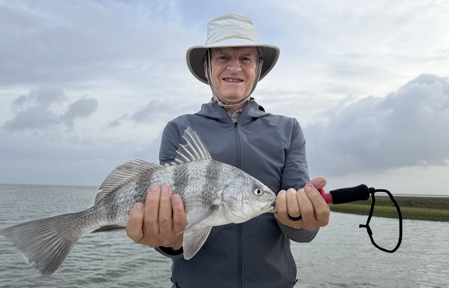 Angler holding freshly caught black drum fish outdoors on water