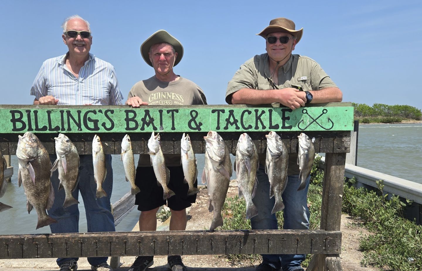 Successful fishing trip displaying catch of black drum and speckled trout hanging from cleaning station