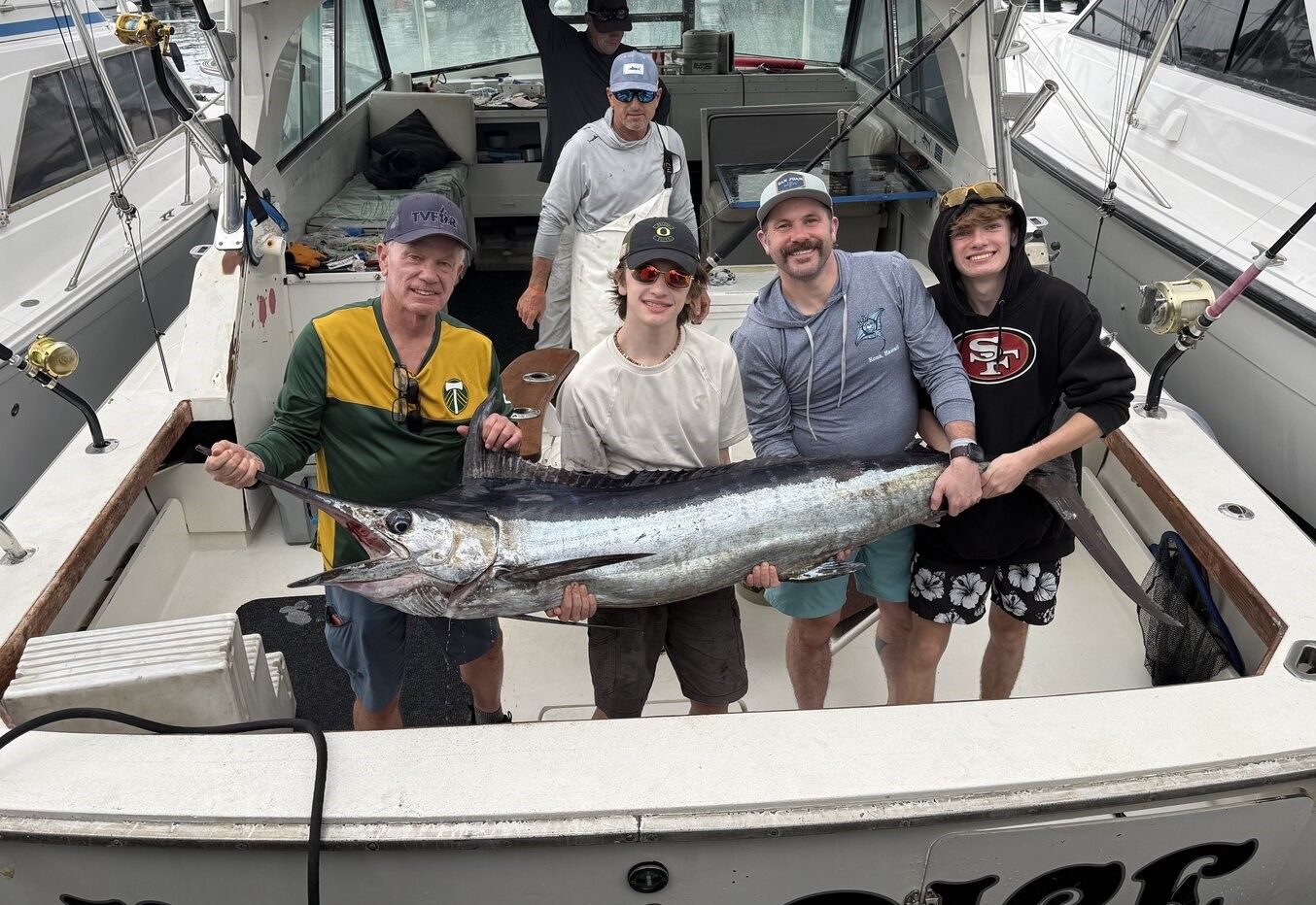 Blue marlin catch displayed on fishing boat deck with fishing crew celebrating successful offshore fishing trip