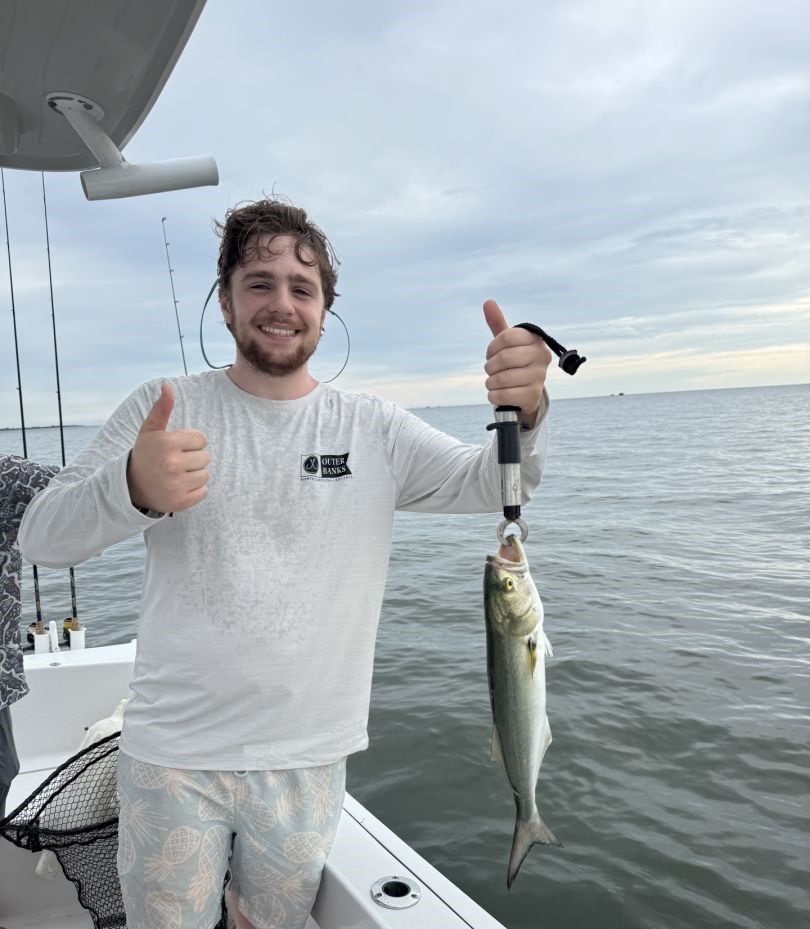 Angler holding freshly caught bluefish on fishing boat