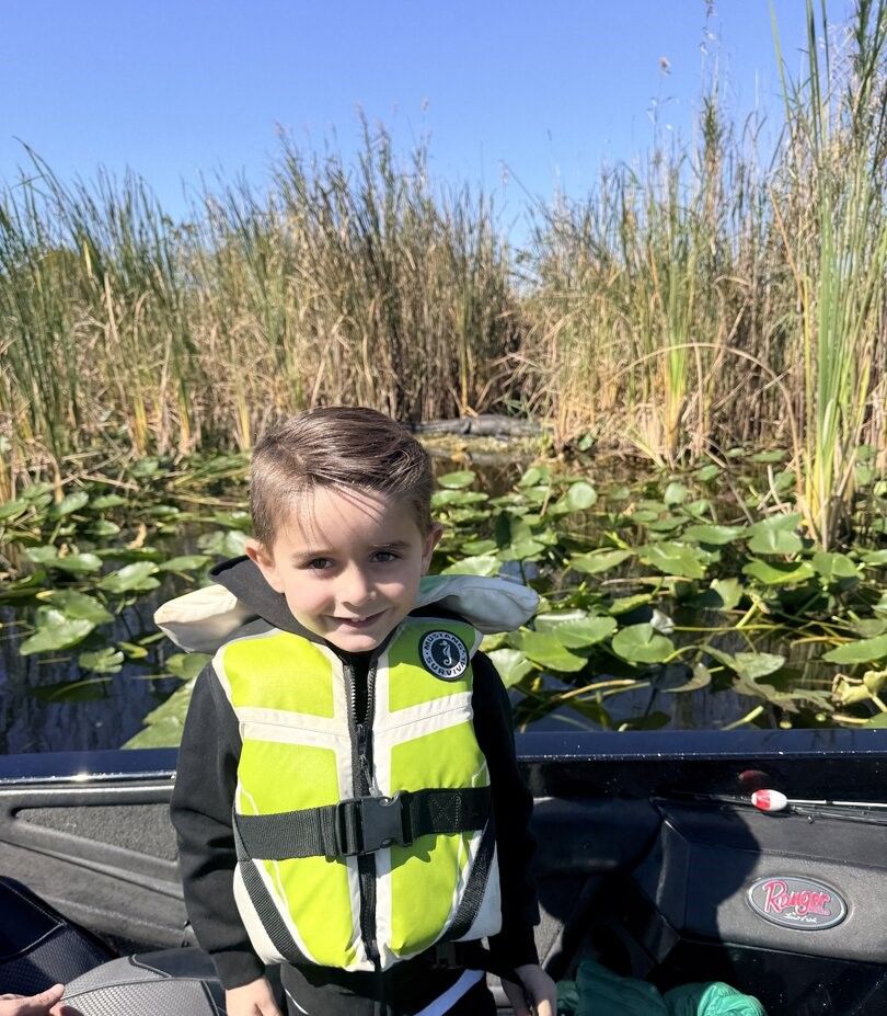 Boat positioned in marsh wetlands with tall grass and lily pads