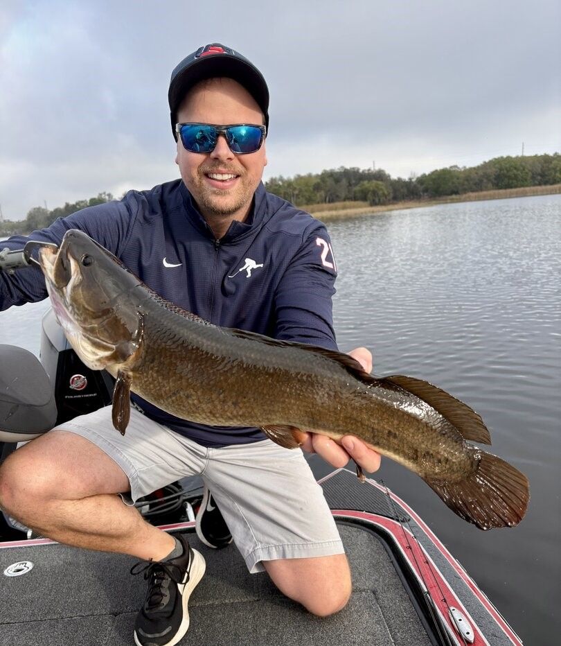 Angler holding freshly caught bowfin on fishing boat