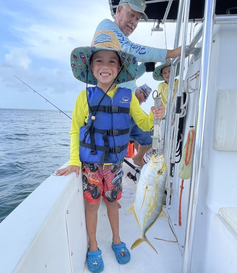 Child holding caught fish on fishing boat deck