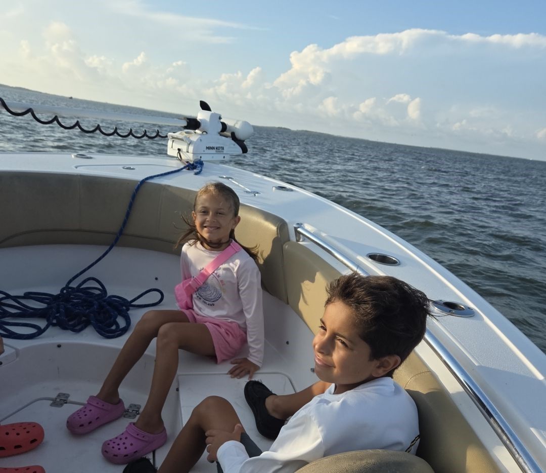 Two children enjoying a day out on a boat surrounded by open water