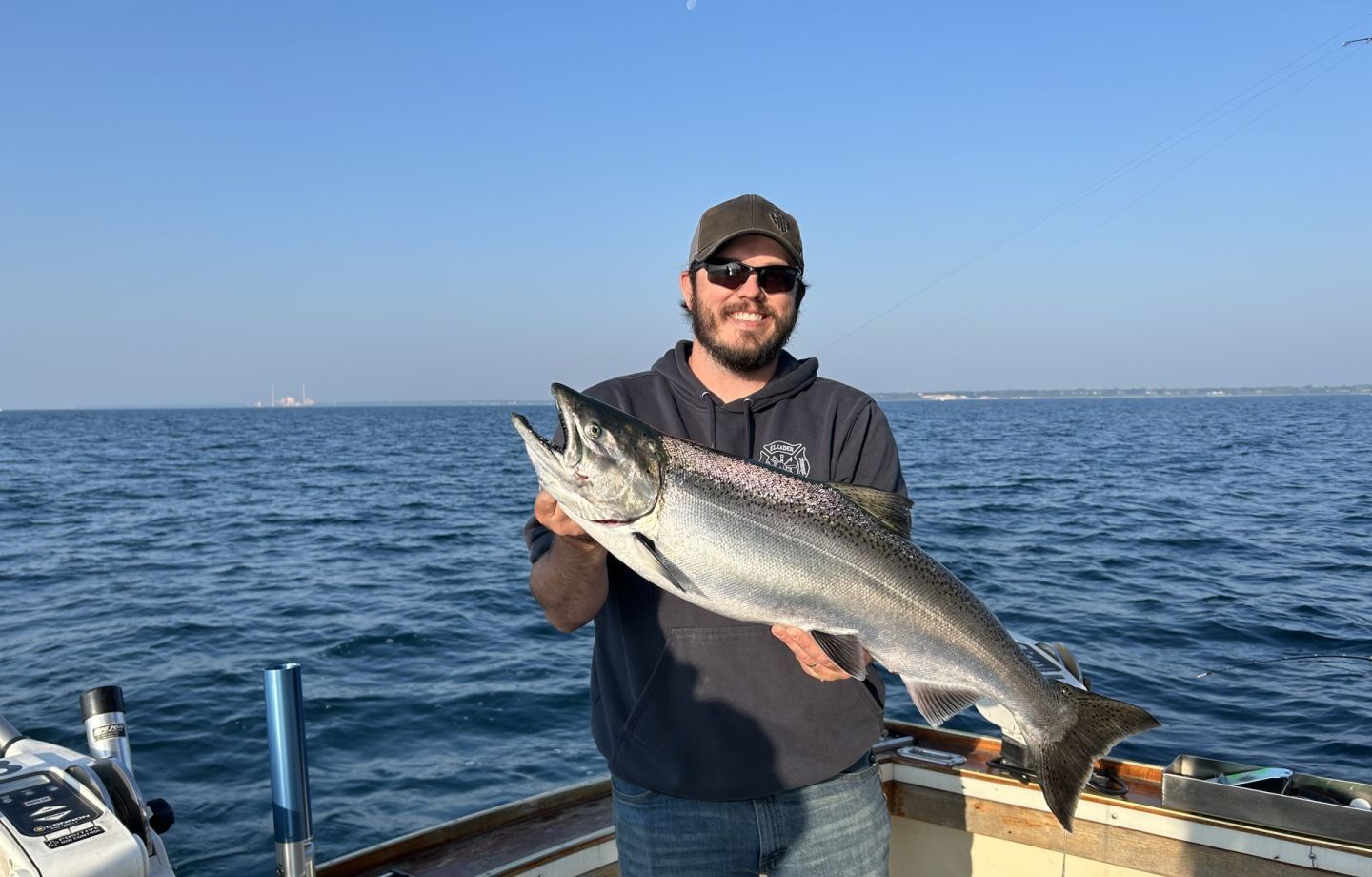 Angler holding large Chinook salmon on fishing boat in open ocean waters