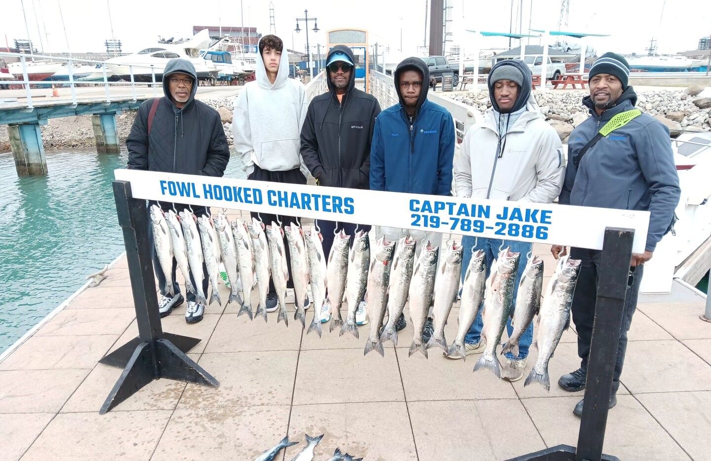 Successful fishing charter displaying catch of coho salmon hanging on dock display rack at marina