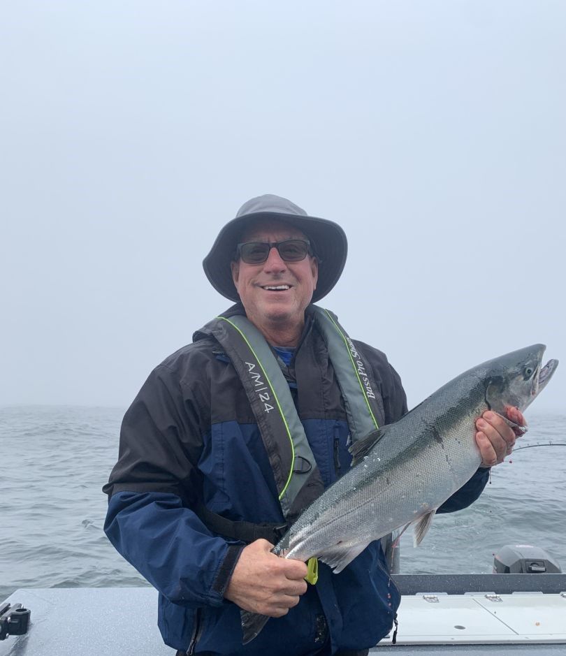 Angler holding freshly caught Coho Salmon on fishing boat