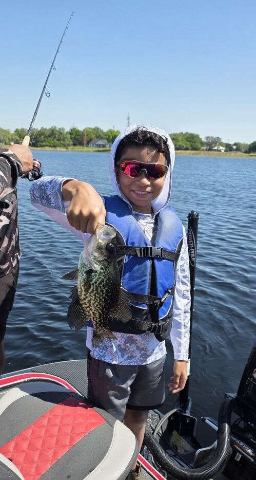 Freshly caught crappie being displayed on fishing boat with fishing rod visible