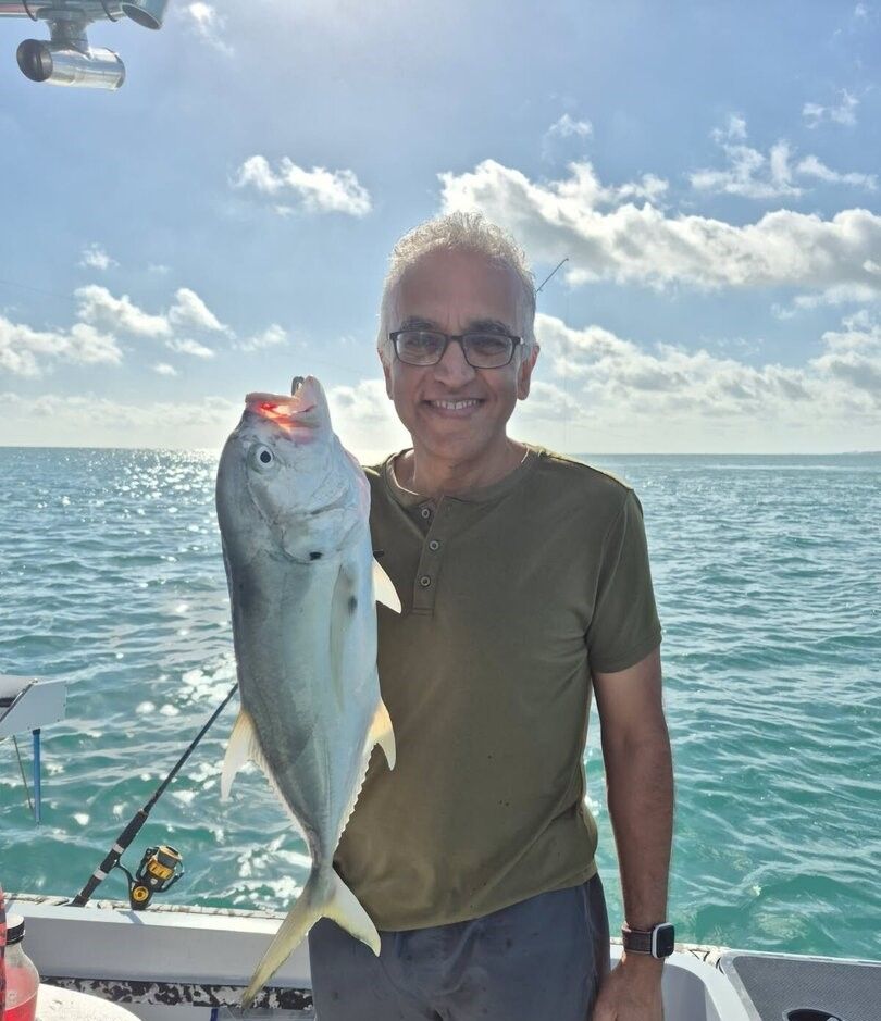 Angler holding freshly caught Crevalle Jack on fishing boat in ocean waters