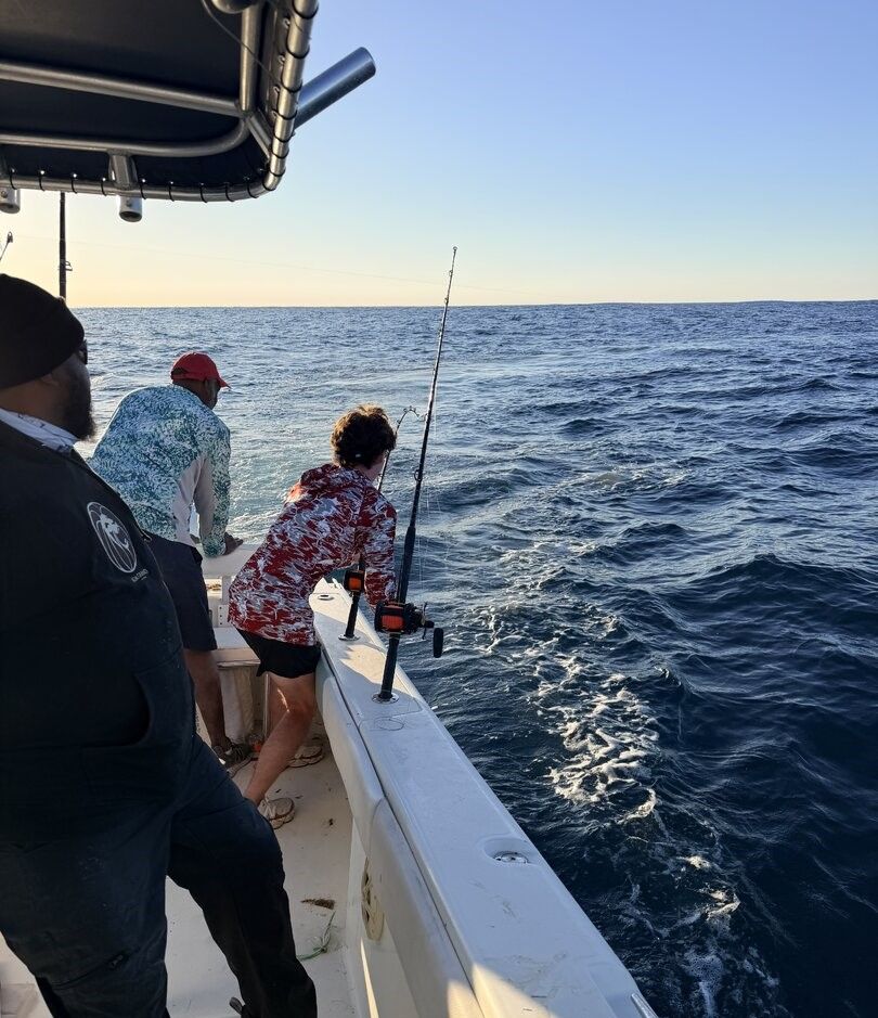 Deep sea fishing from boat deck with fishing rod extended over ocean water