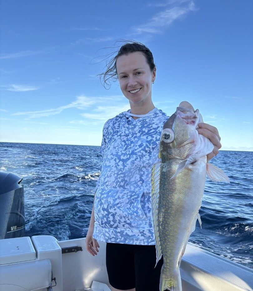 Angler holding caught fish on boat in open ocean waters