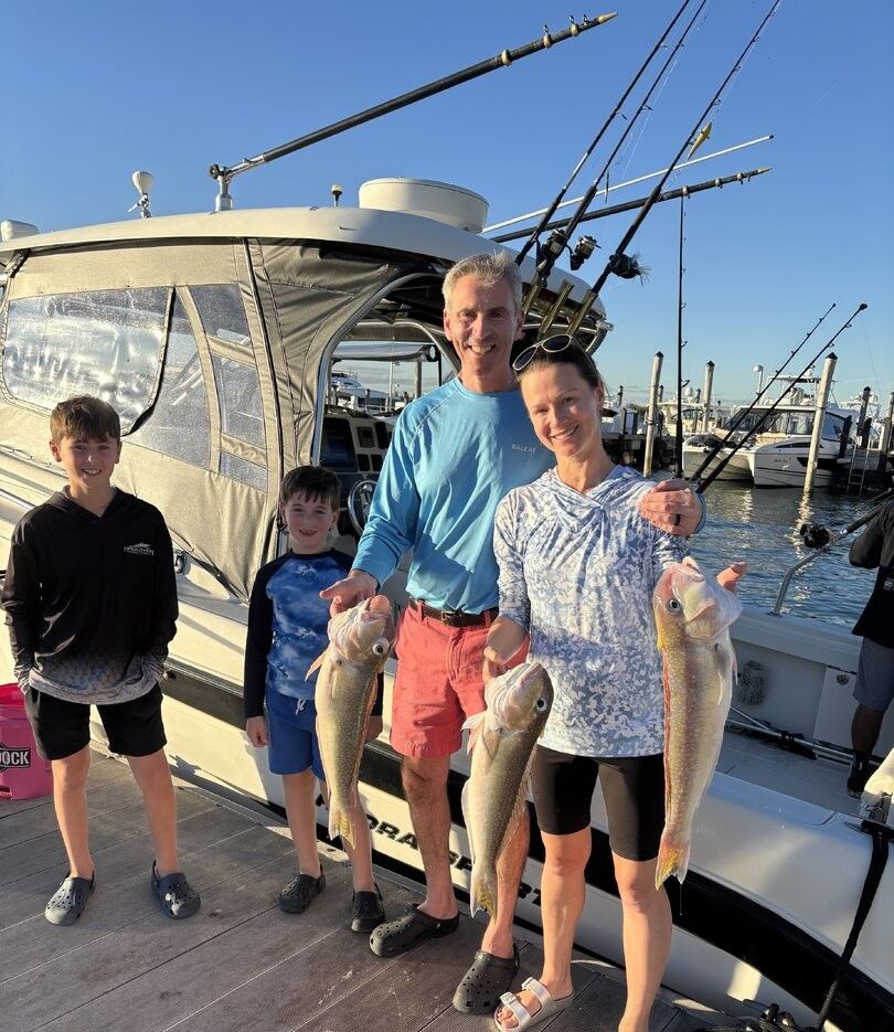 Family fishing trip displaying catch of three fish species on boat dock