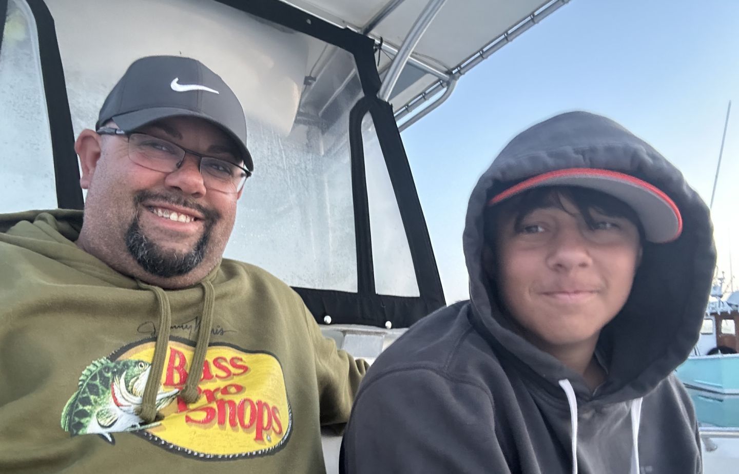 Two people on a fishing boat with enclosed cabin during outdoor fishing trip