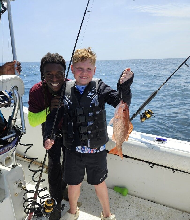 Fresh caught fish displayed on fishing boat deck with fishing rods and ocean water visible in background