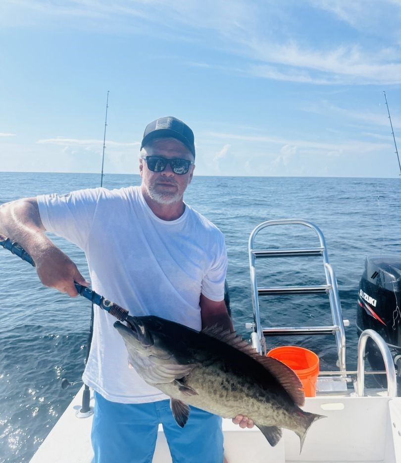 Angler holding large gag grouper on fishing boat in ocean waters