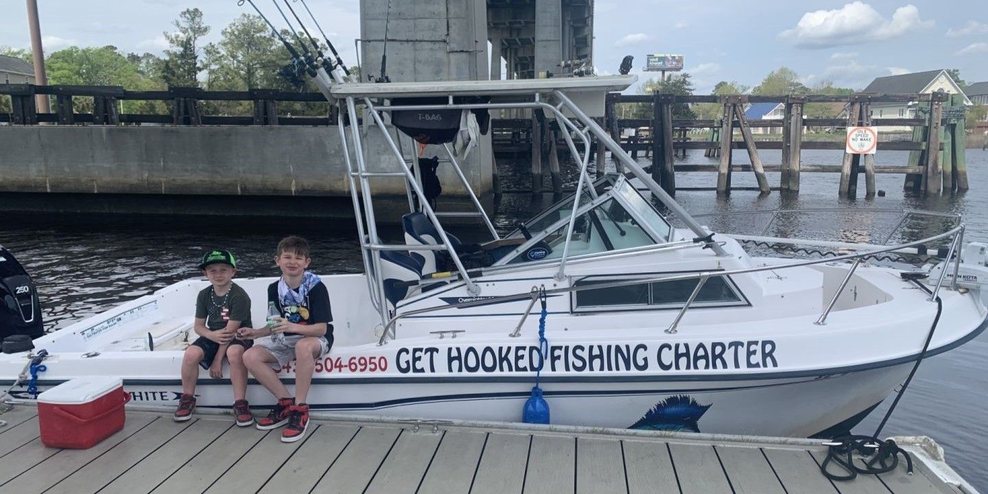 White fishing charter boat docked at marina with Get Hooked Fishing Charter signage