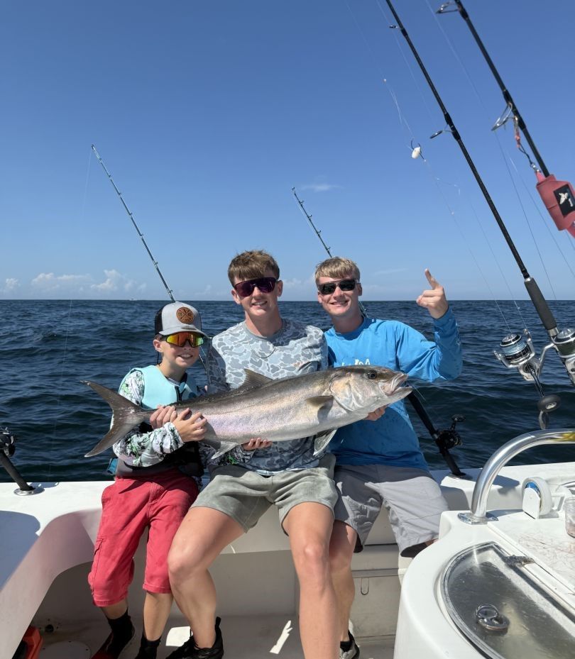 Fishing charter crew displaying freshly caught Greater Amberjack on boat deck with fishing rods