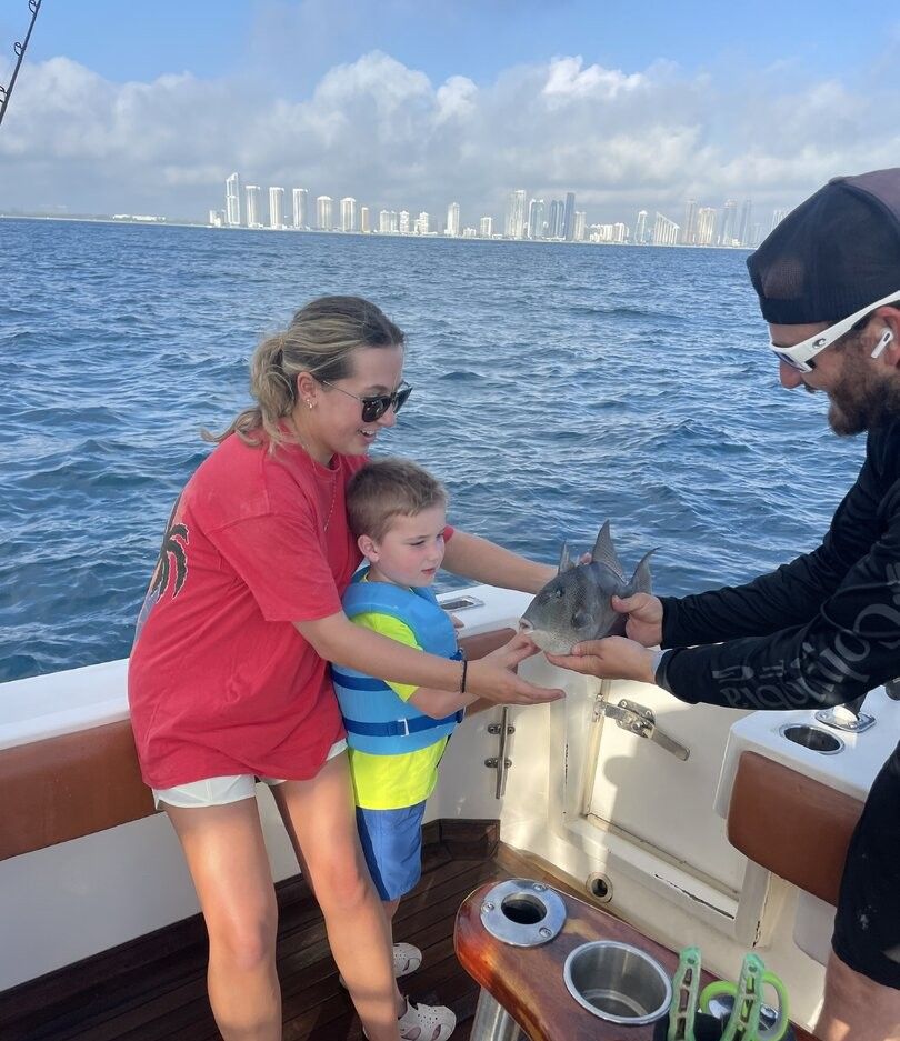 Grey triggerfish being handled on fishing boat with city skyline in background