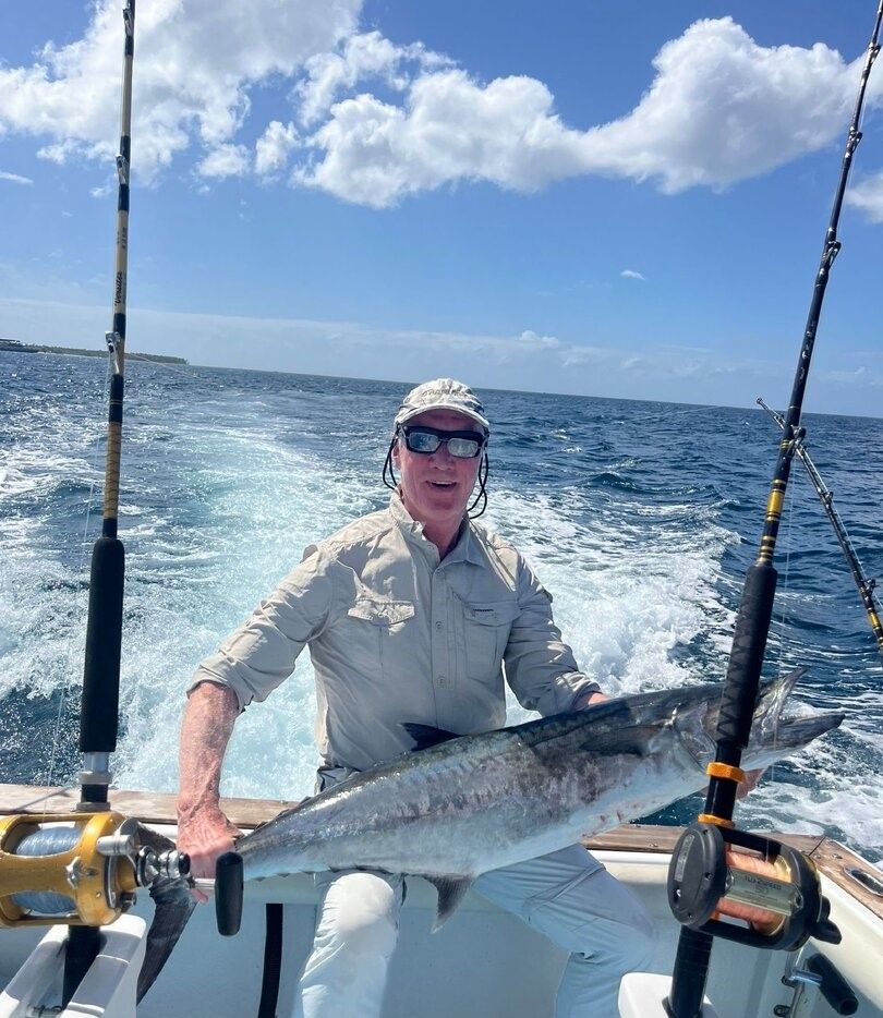 Angler holding freshly caught King Mackerel on fishing boat in ocean waters