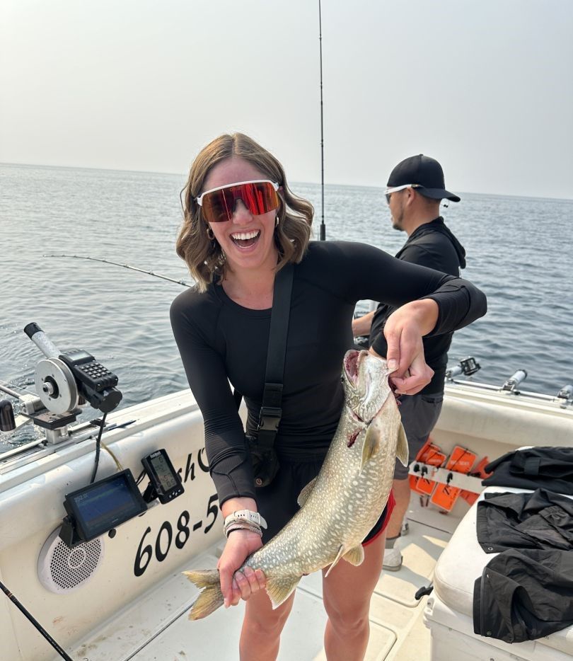 Angler holding freshly caught lake trout on fishing boat