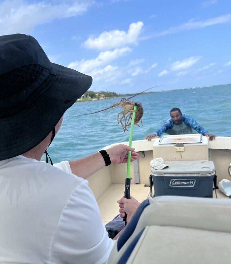 Lobster caught on fishing pole held over boat on ocean water