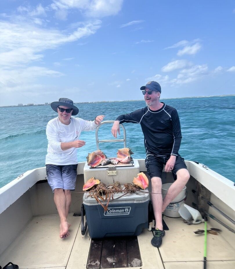 Fresh caught lobsters and conch shells displayed on boat deck with cooler