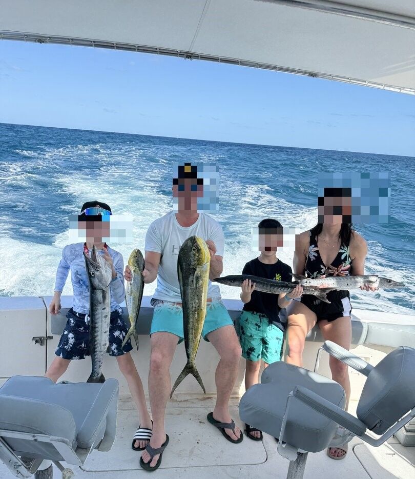 Fishing charter displaying caught mahi mahi and great barracuda on boat deck in open ocean