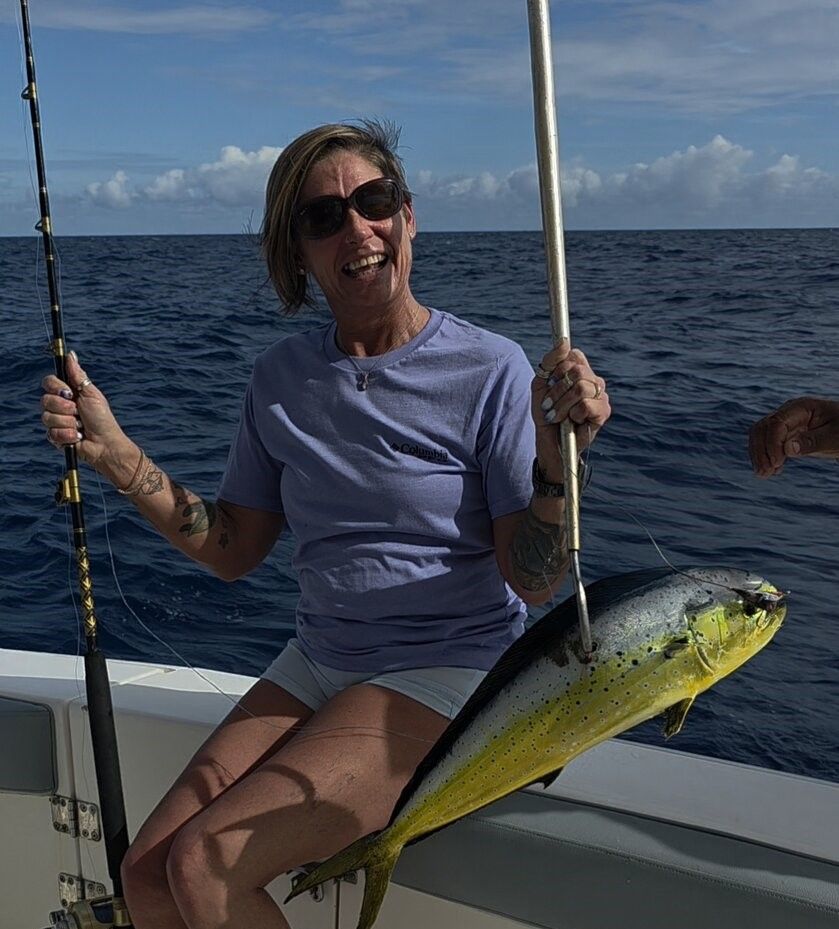 Freshly caught mahi mahi being held on fishing boat deck over ocean waters