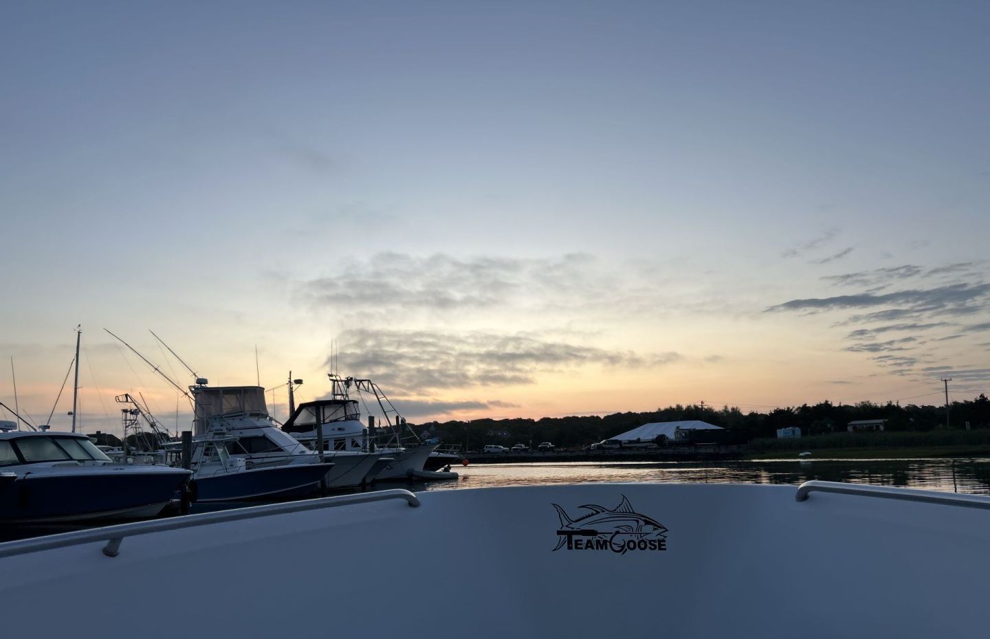 Marina at sunset with fishing boats docked, view from boat deck with Team Goose logo