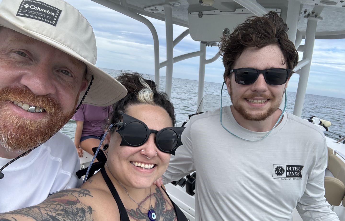 Three people on a boat deck over open ocean water during a boating excursion
