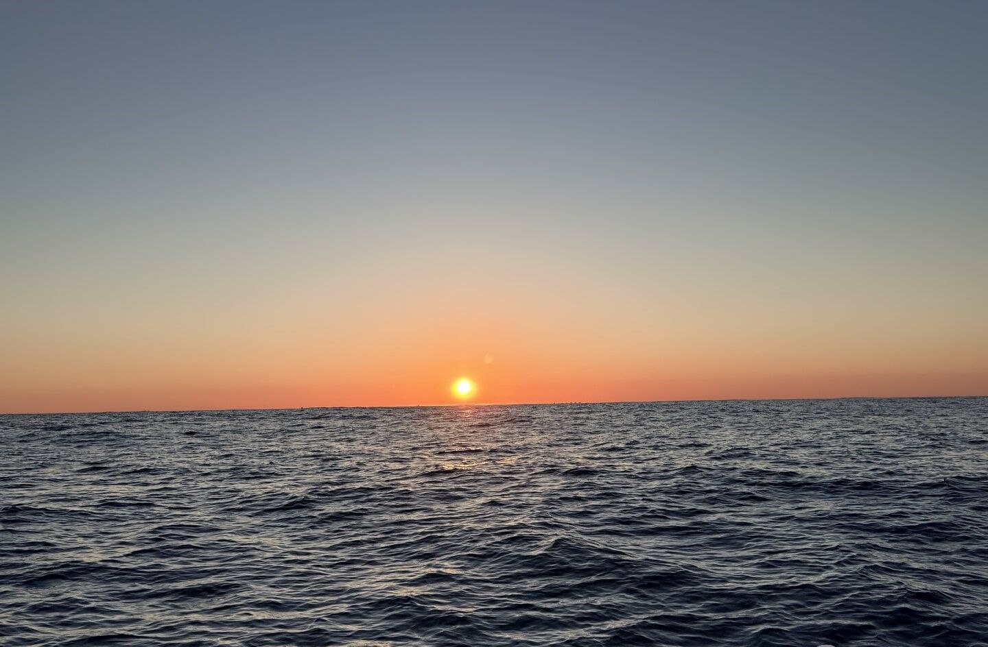 Ocean sunset with calm waters and orange sky horizon view