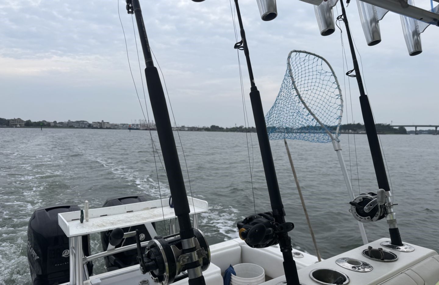 Fishing boat deck with multiple fishing rods and reels set up for offshore fishing with wake visible in water