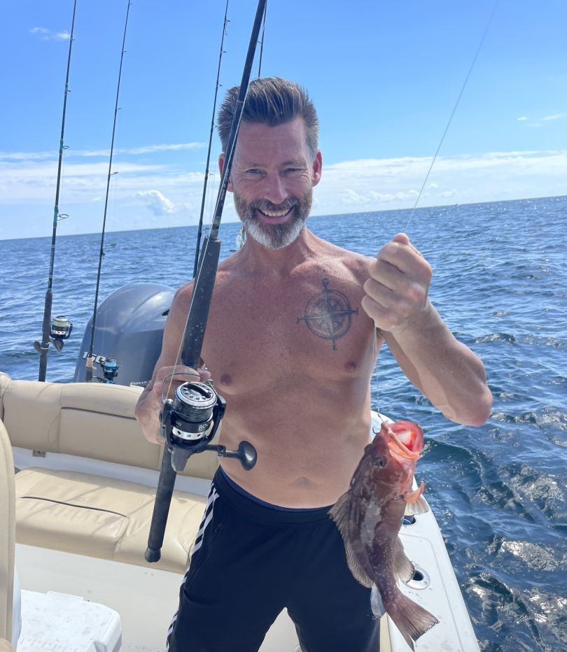 Fishing boat with caught red grouper and fishing rod on ocean water