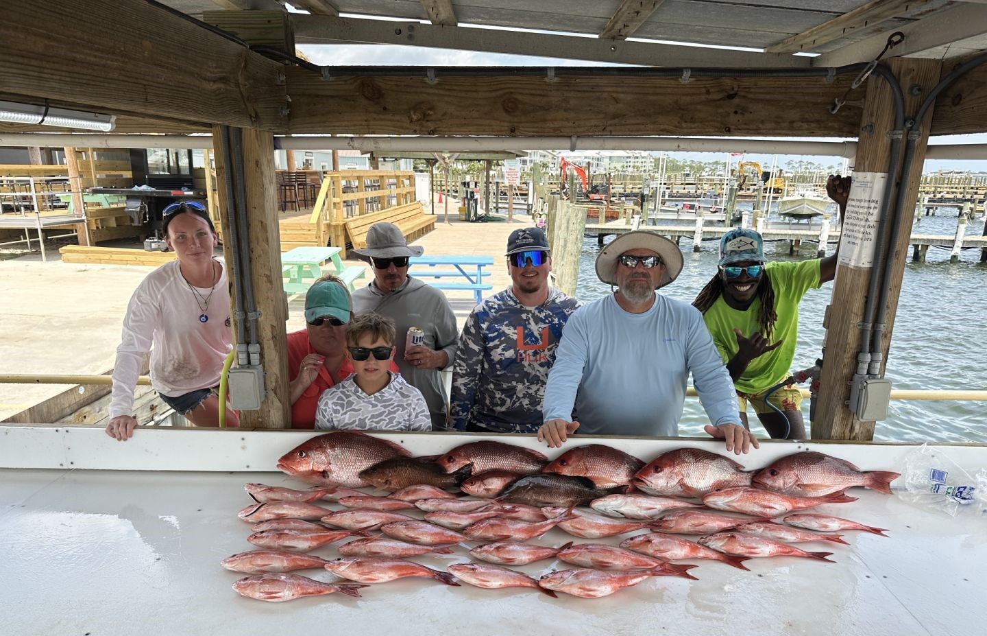 Fishing charter group displays large catch of red snapper on boat deck at marina