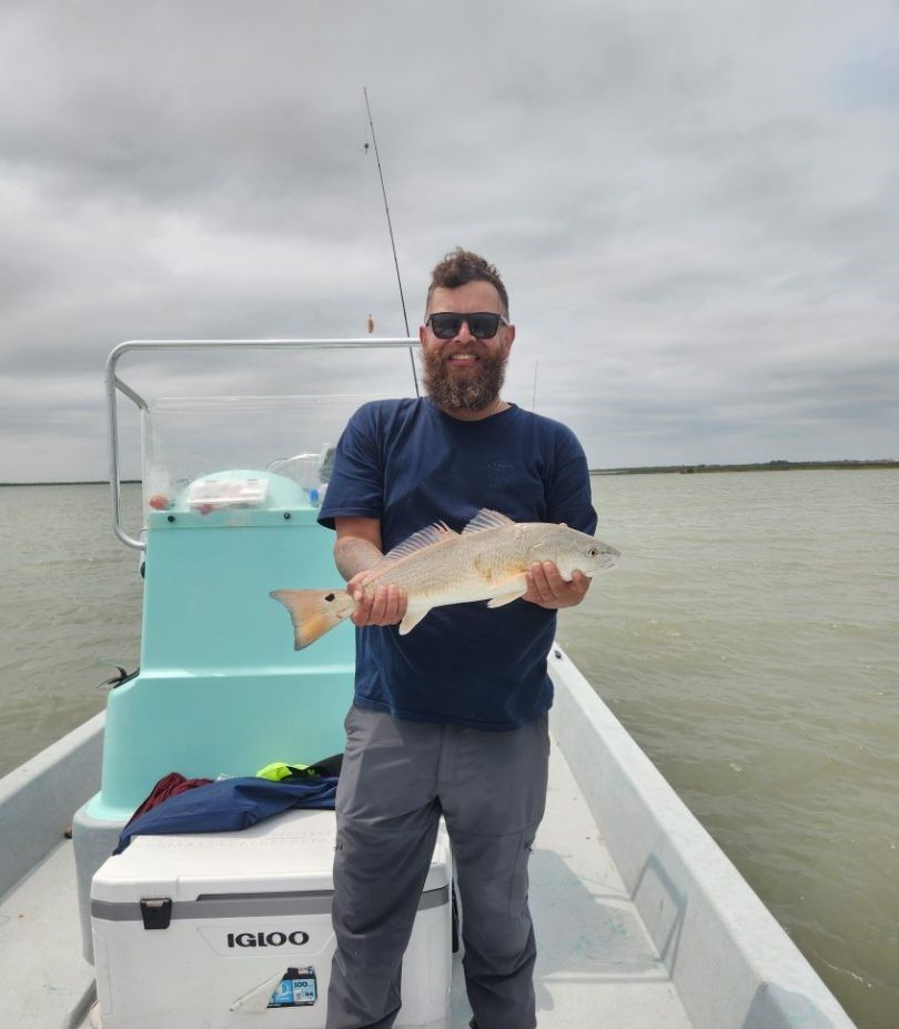 Angler holding caught redfish on fishing boat