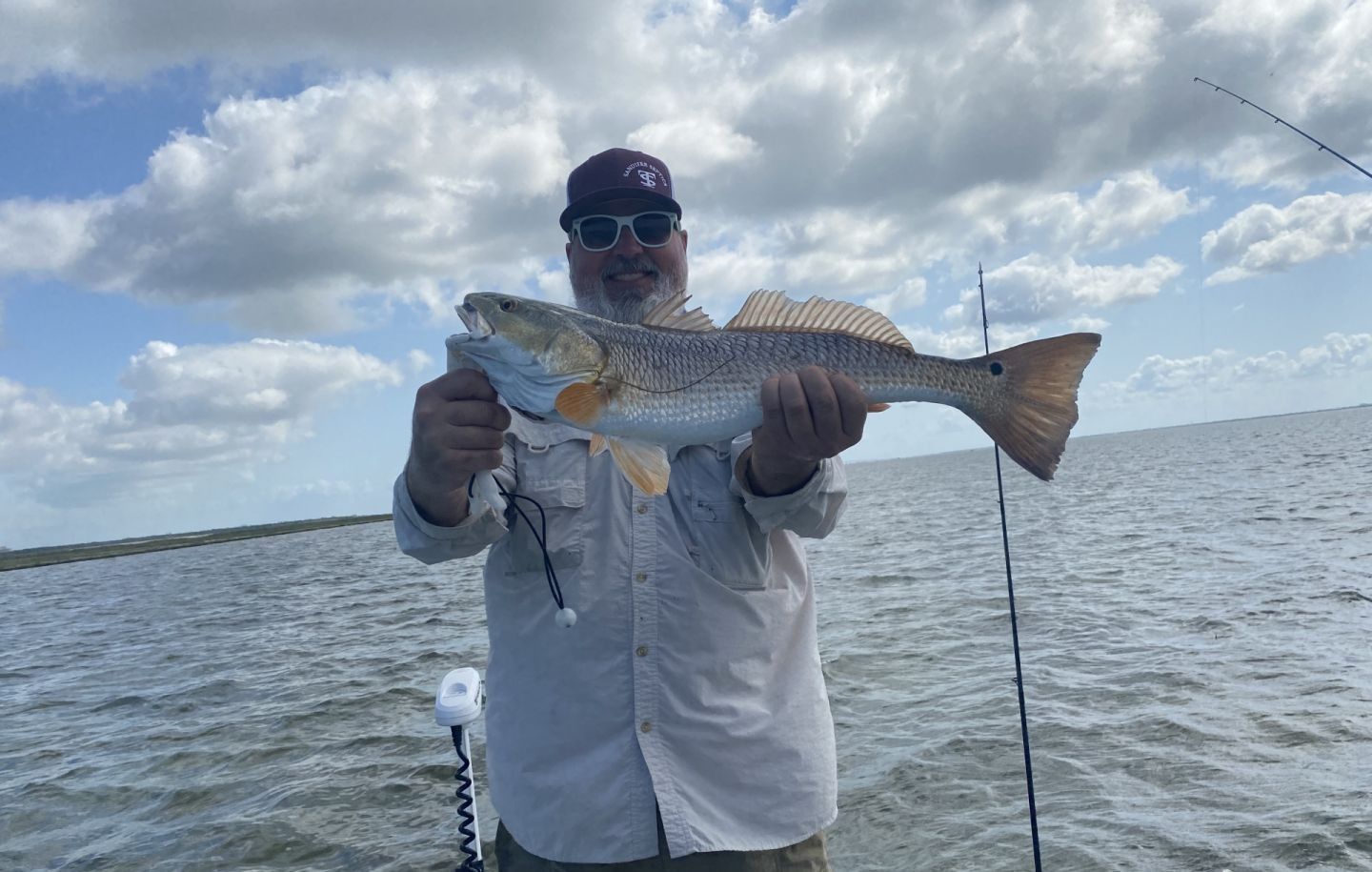 Angler holding caught redfish on fishing boat in open water