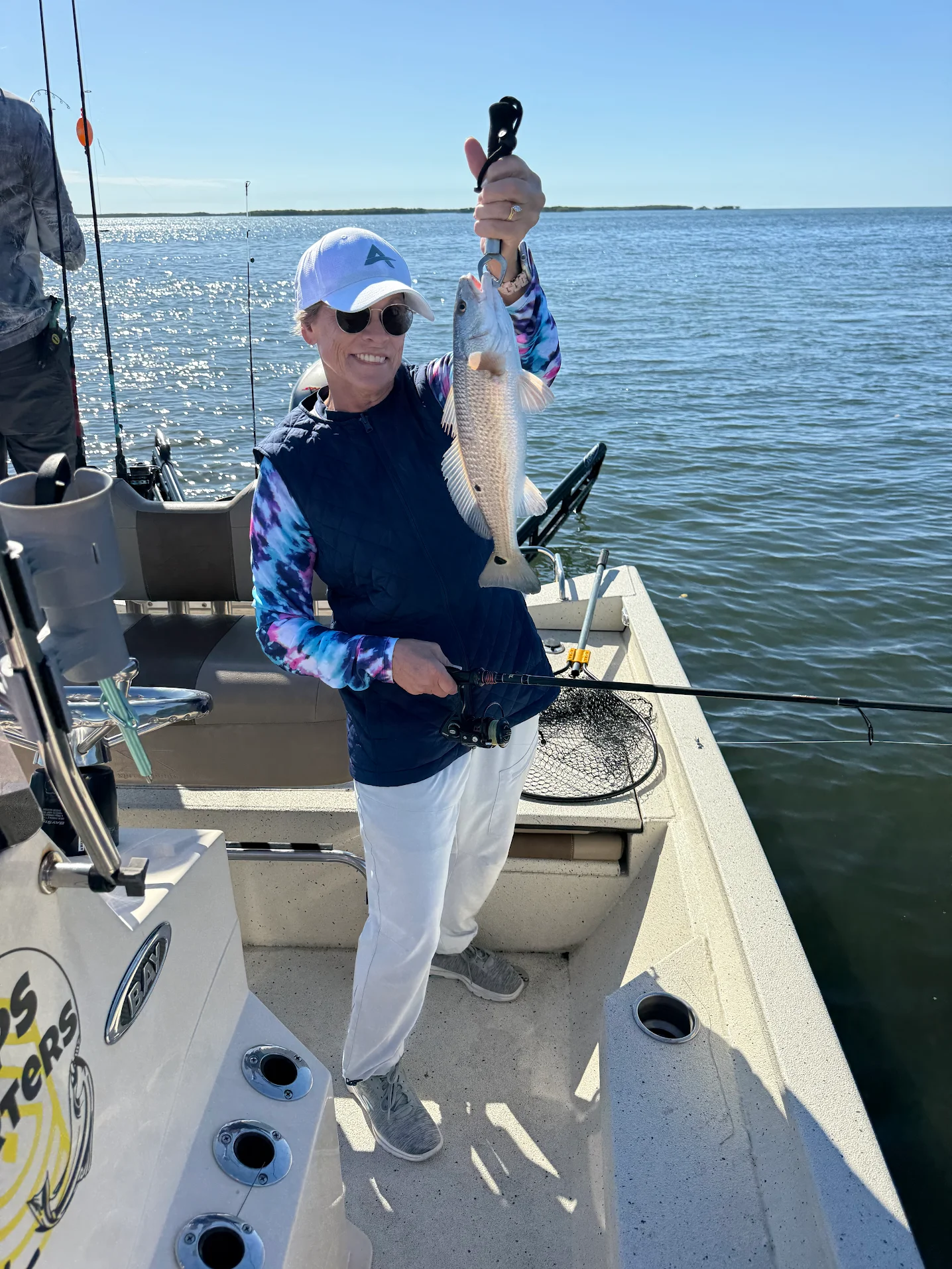 Angler holding caught redfish on fishing boat during outdoor fishing trip