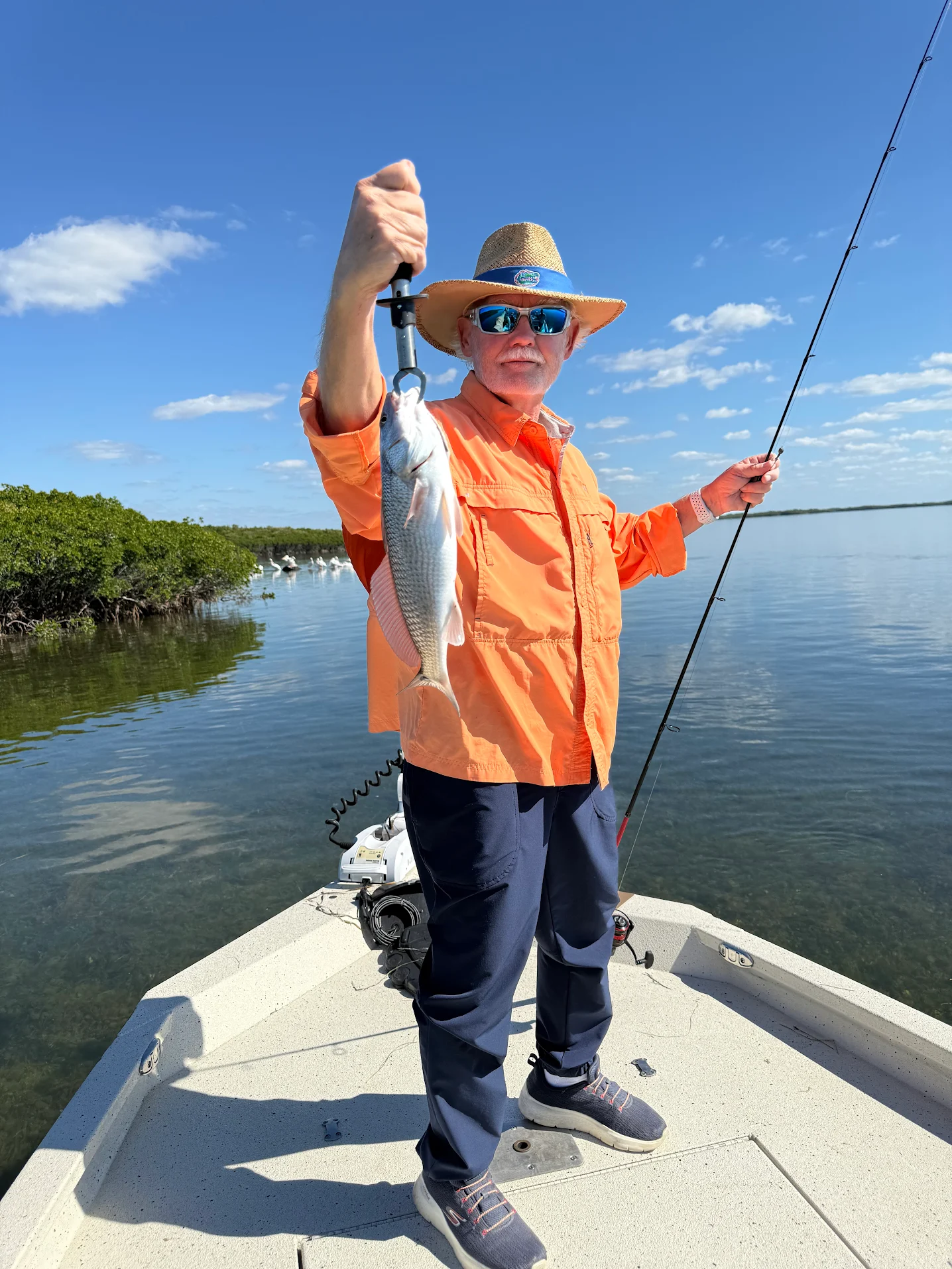 Angler holding caught redfish on fishing boat in shallow water