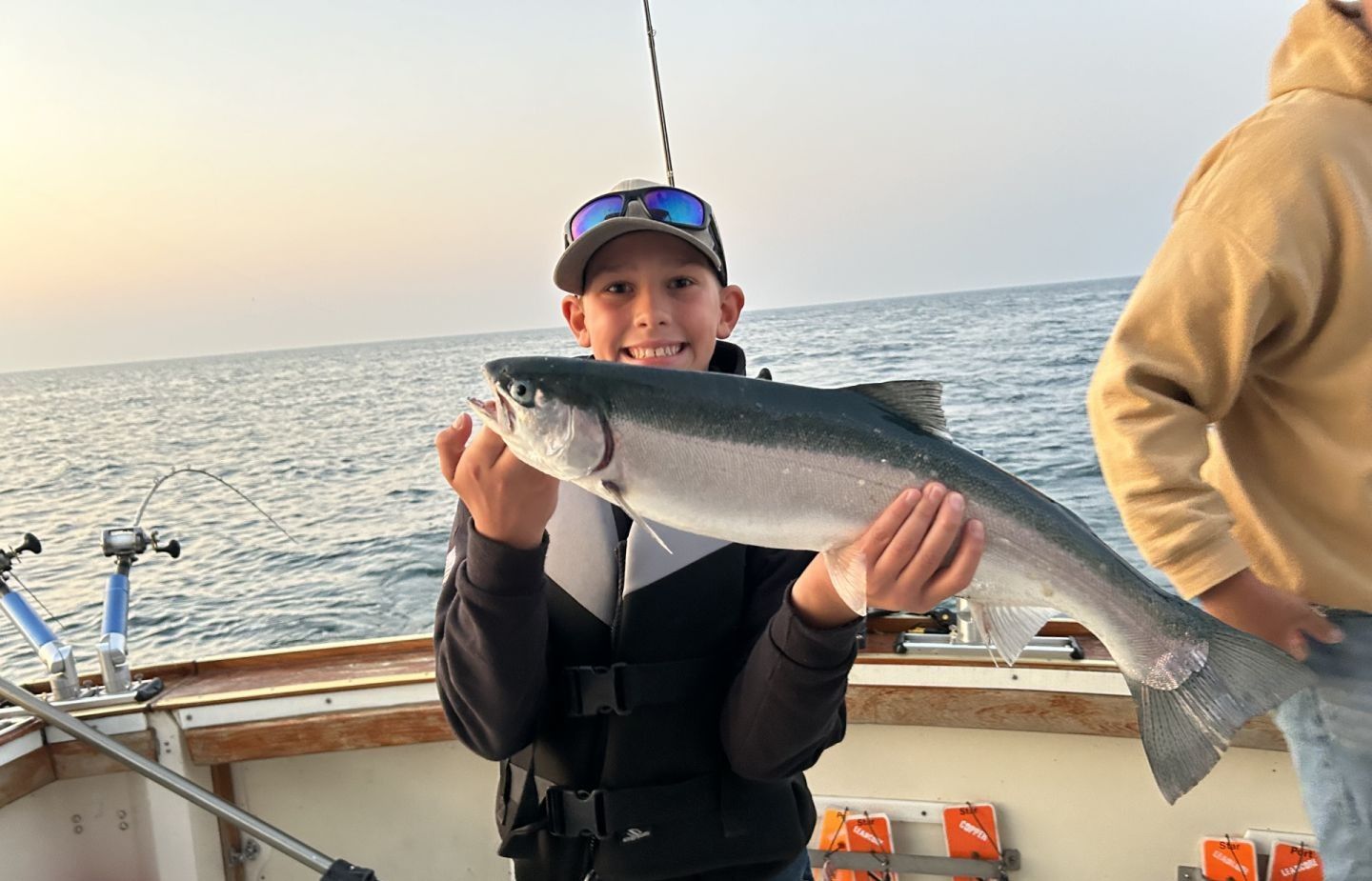 Freshly caught salmon being held on fishing boat deck over ocean waters