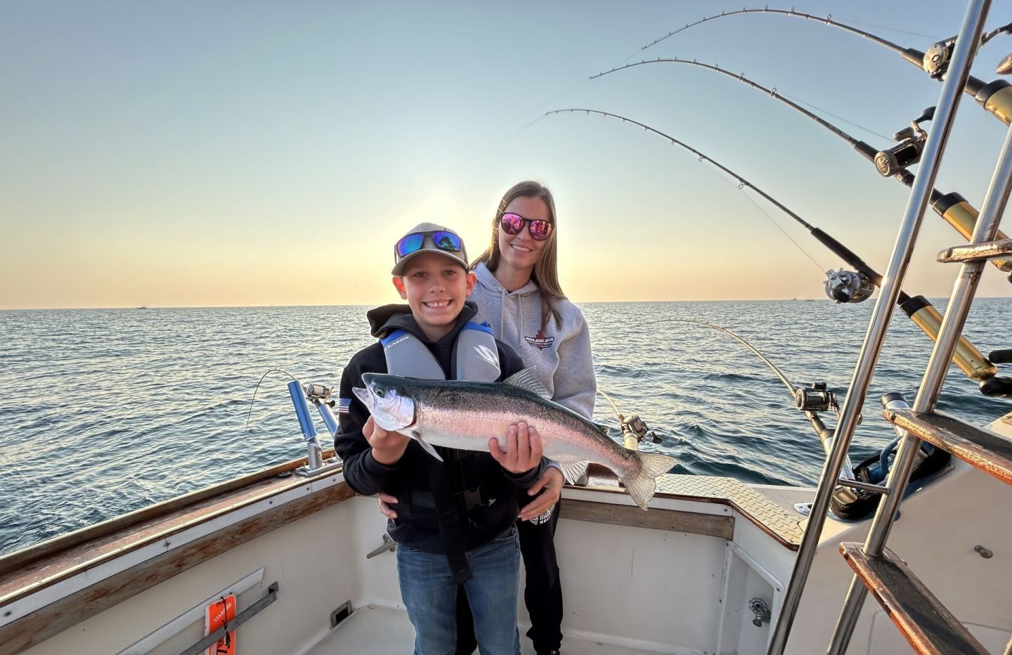 Fishing charter success with salmon catch on boat deck with fishing rods and ocean backdrop