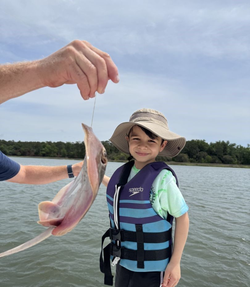 A lone fisherman landing a catch at an unknown location.
